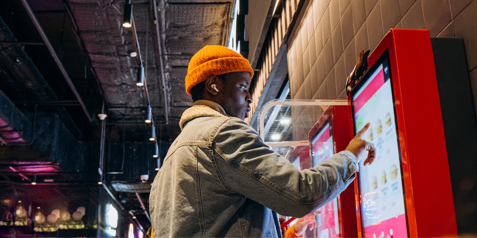 man uses digital signage self-service kiosk display to order a snack